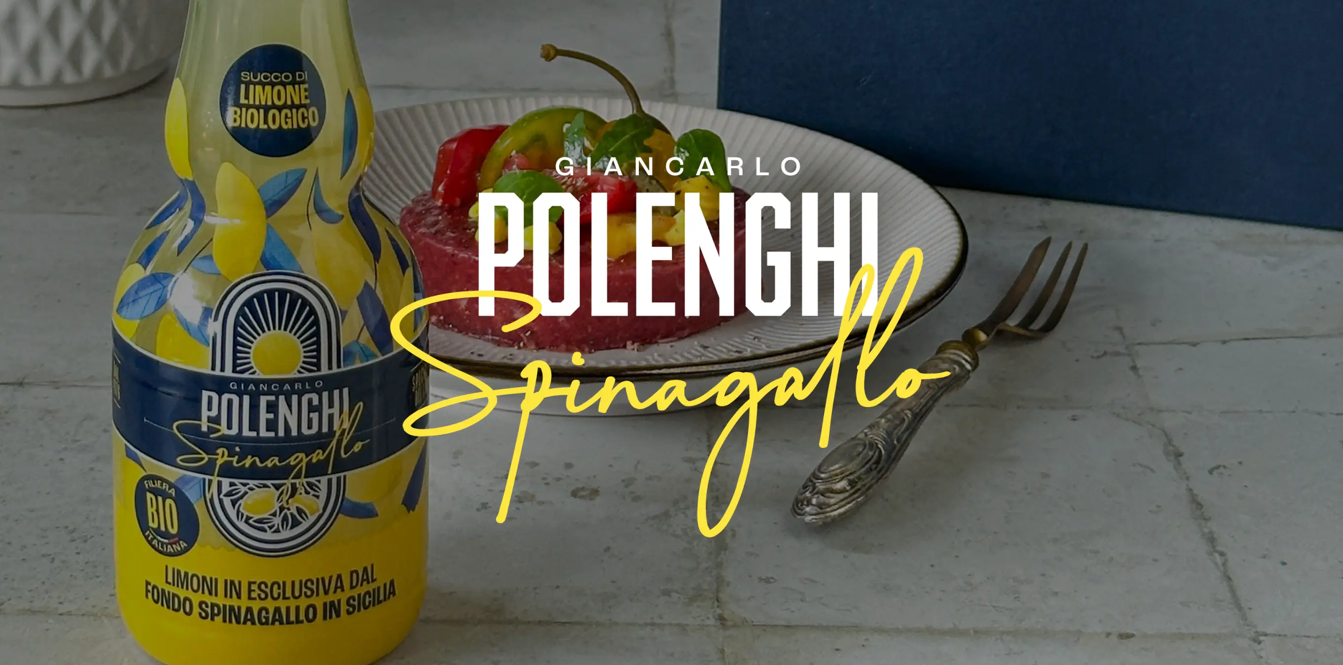 Giancarlo Polenghi lemon juice bottle in yellow and blue carafe next to gourmet dish and branded box