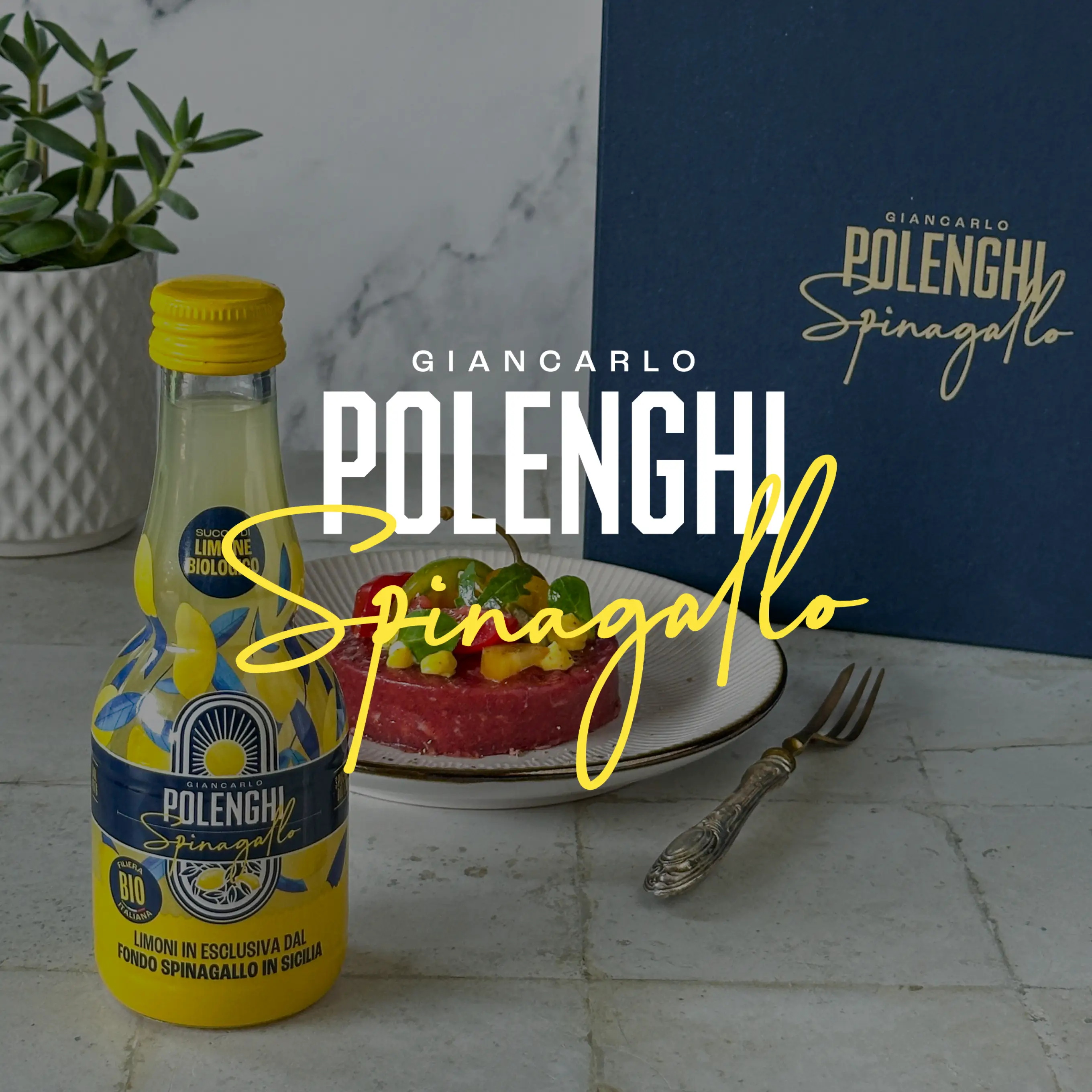 Giancarlo Polenghi lemon juice bottle in yellow and blue carafe next to gourmet dish and branded box