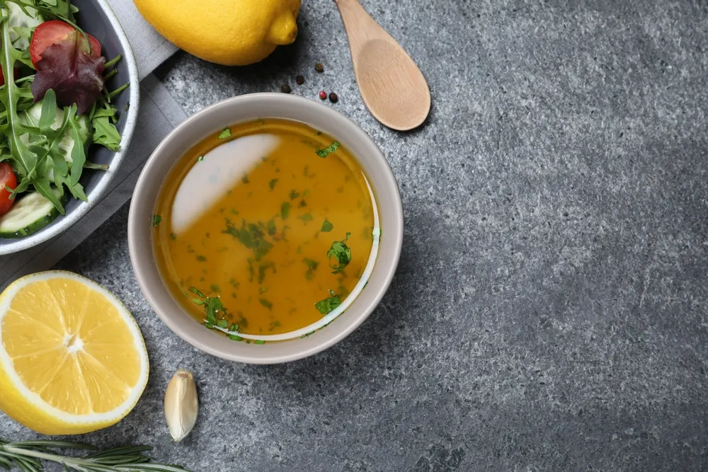 Bowl of lemon and herb marinade on a stone surface.