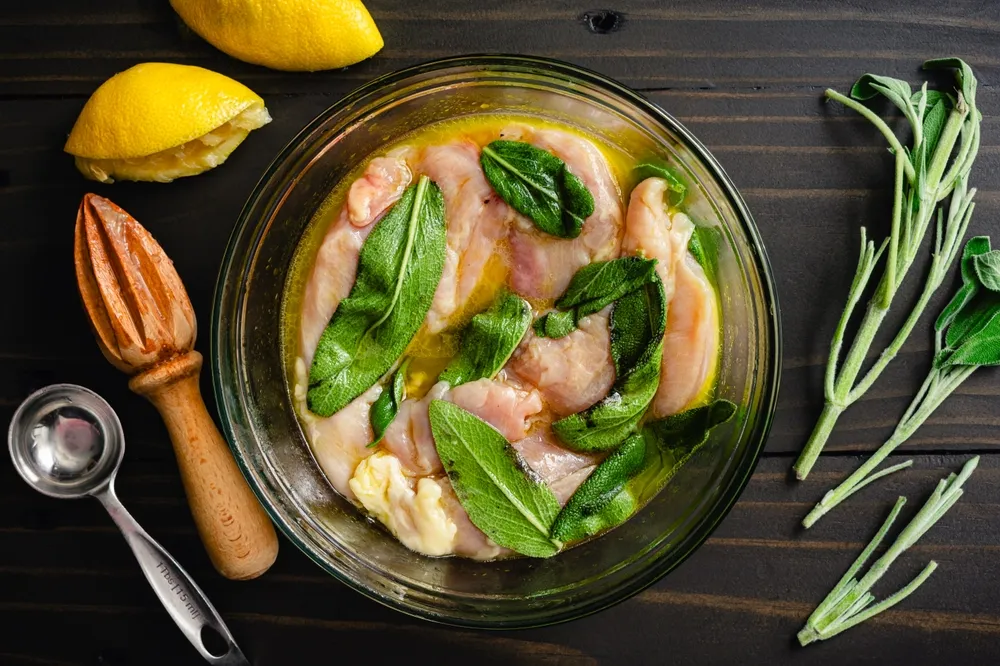 Lemon and sage chicken marinade in a glass bowl.