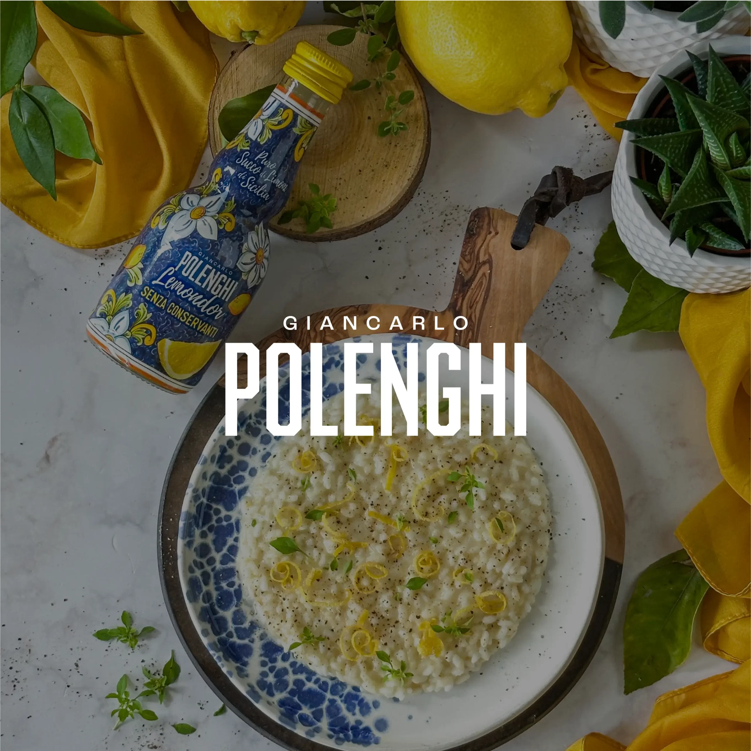 Bottiglia Polenghi di succo di limone accanto a un piatto di risotto al limone guarnito con scorza e erbette, limoni, tagliere e tovaglia gialla.