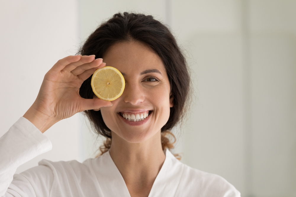 Una donna sorridente con una fetta di limone sopra un occhio.